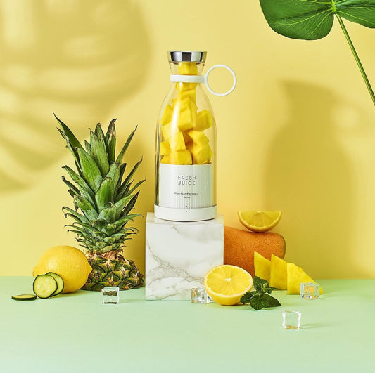 Bottle of 'Fresh Juice' with pineapple and lemon on a yellow background